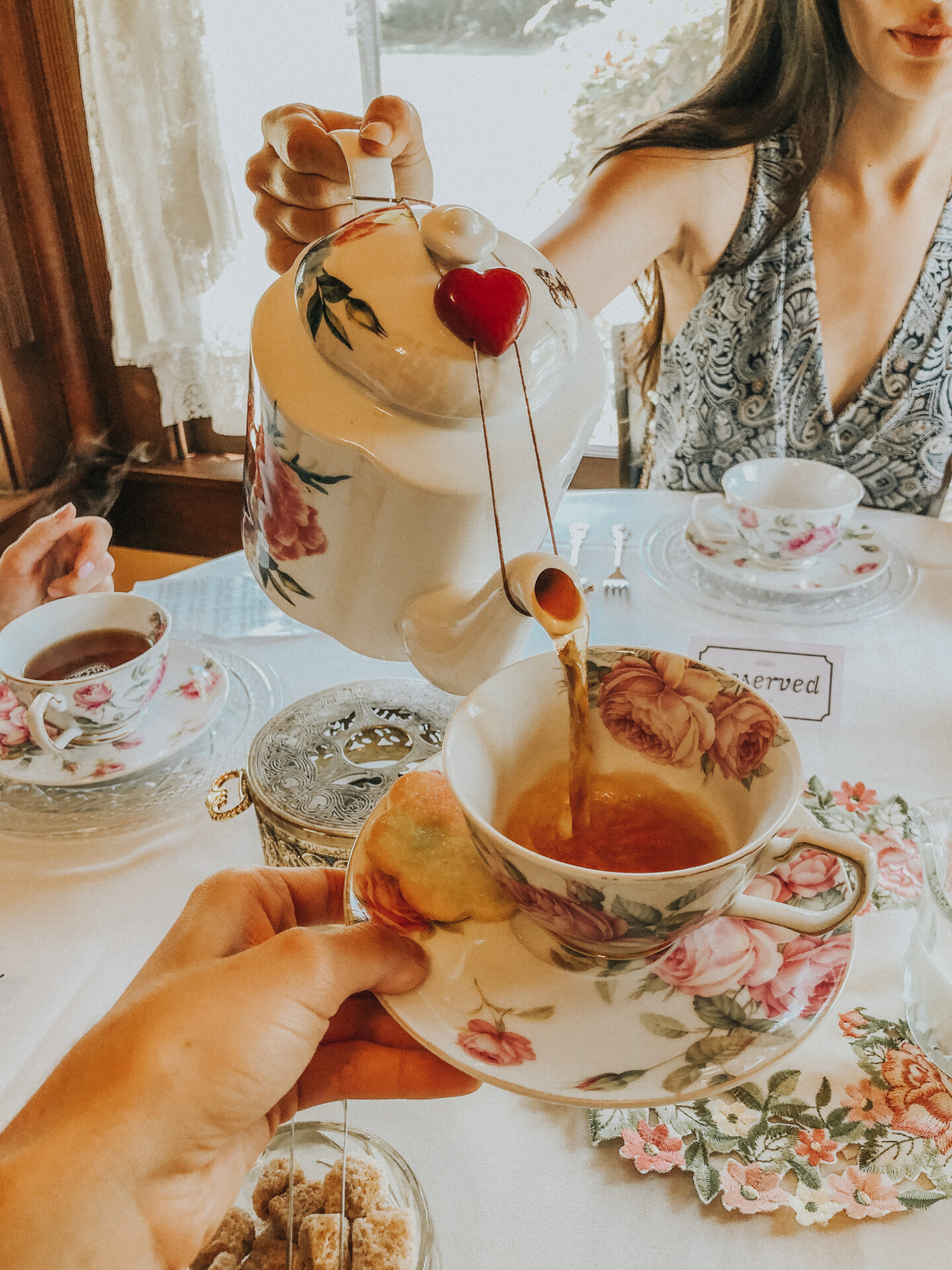 Things to do in Old Town San Diego Afternoon Tea at Coral Tree, woman pouring tea pot into decorative tea cup