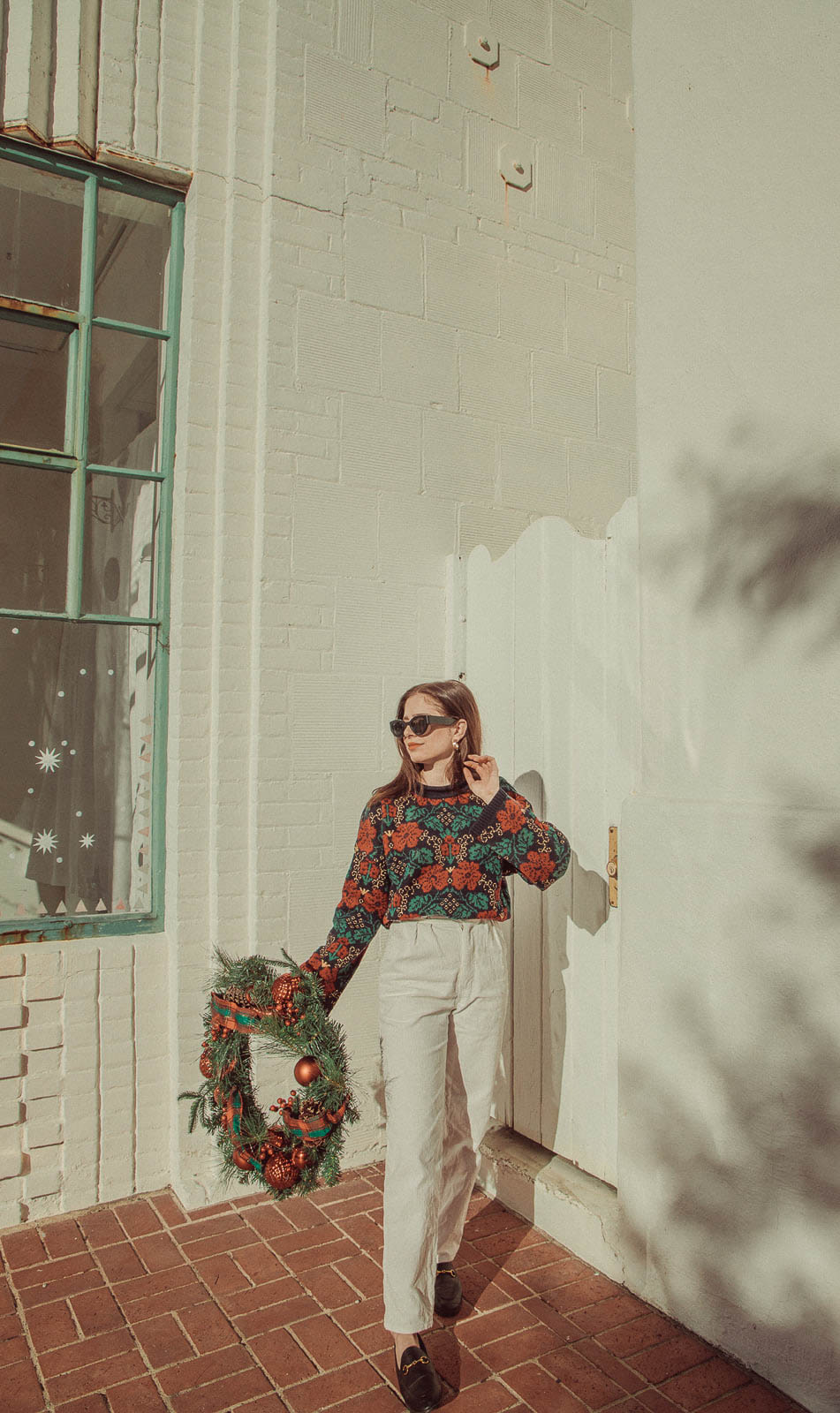 Photoshoot with Christmas wreath, woman wearing Christmas sweater - 5 Creative Christmas Photoshoot Ideas to Try This Season