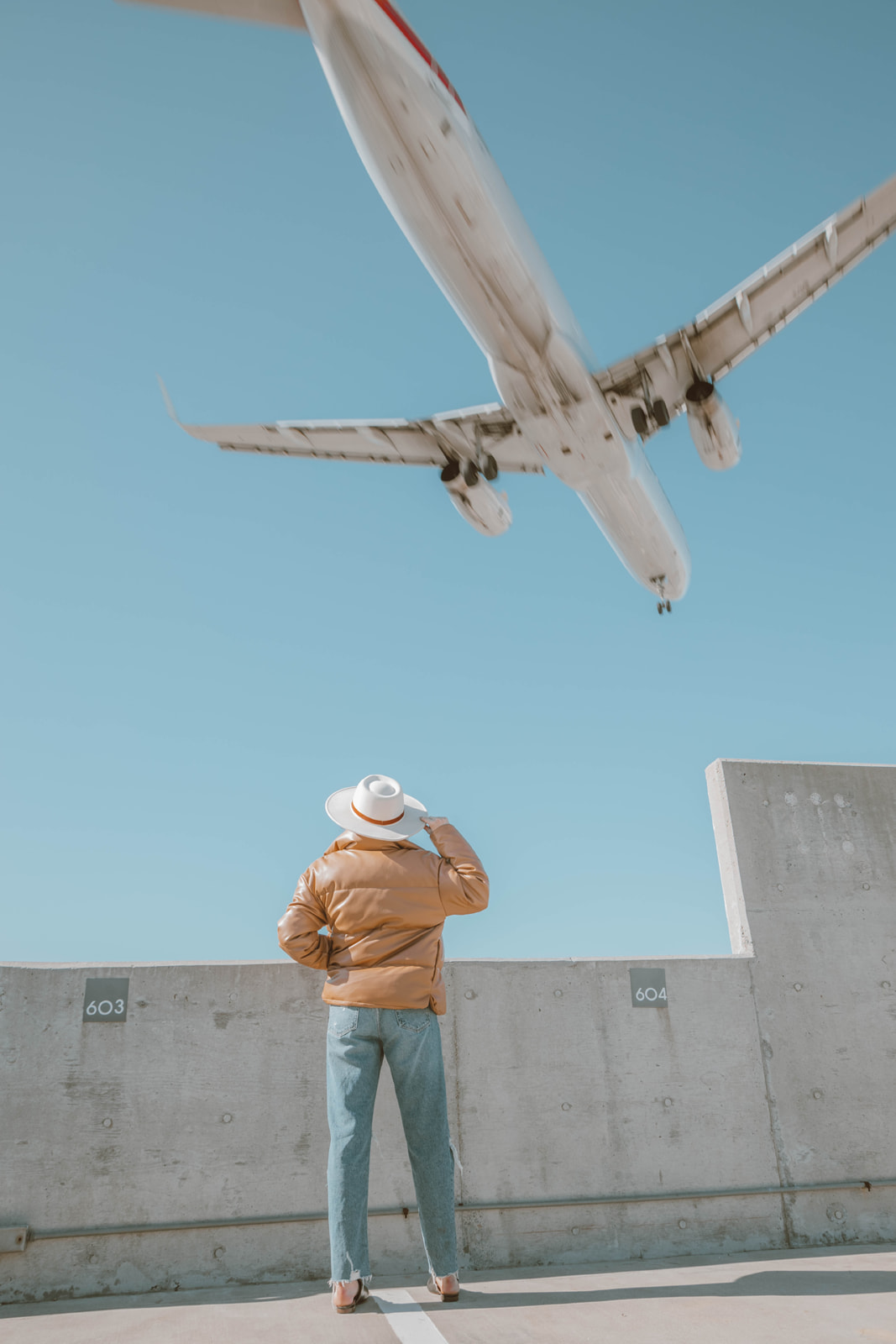 Instagrammable Places in Little Italy San Diego, photoshoot on parking garage roof with airplane flying above model's head